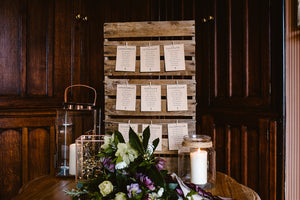 Brown floral seating plan cards attached to board with pegs