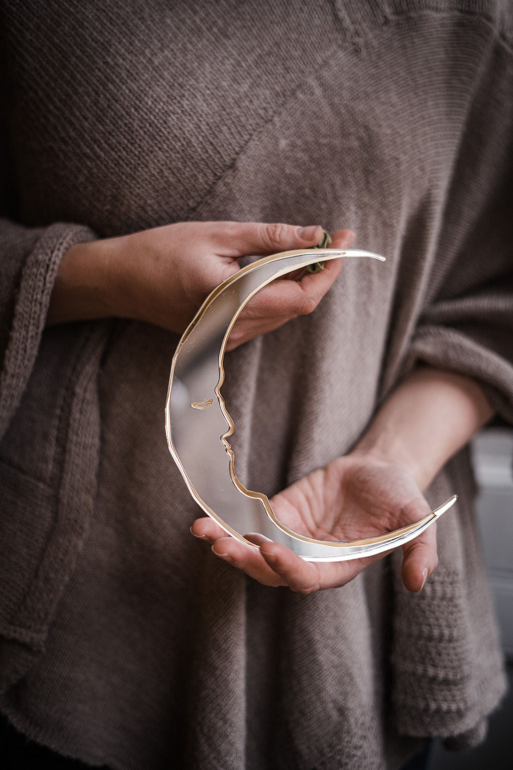 a person holding a small crescent moon shaped mirror.