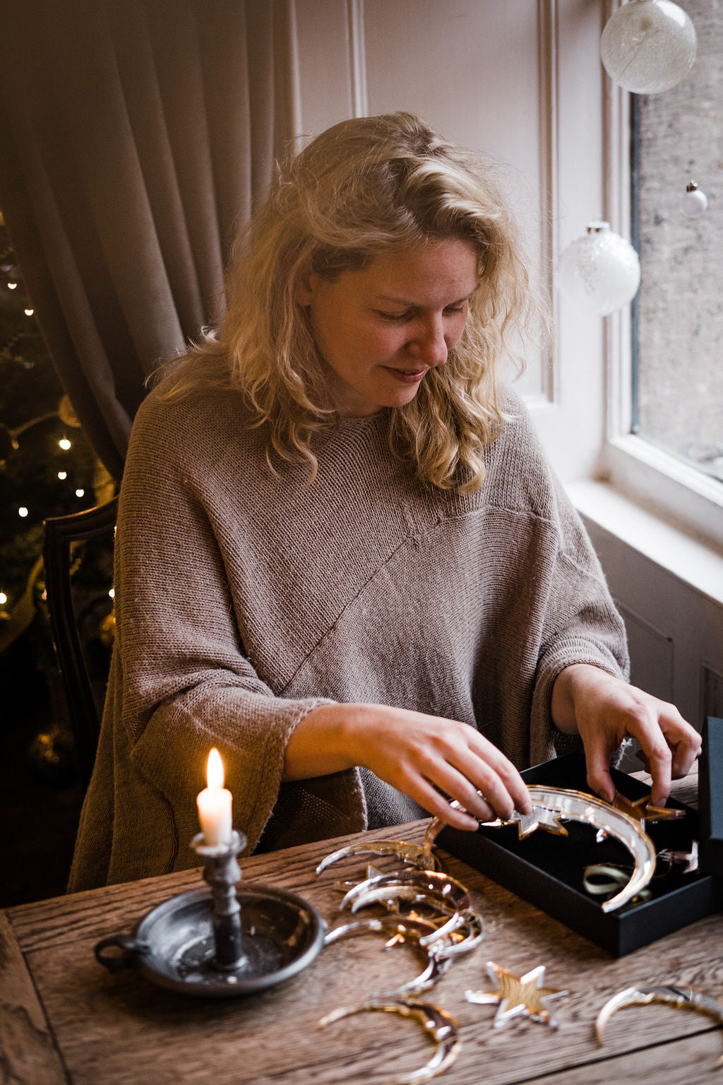 Star and crescent moon shaped christmas baubles being placed into gift box.