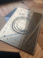 Load image into Gallery viewer, A decorative tarot card with etched design of a crescent moon, stars and the words &#39;the moon laying flat.
