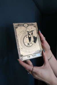 A decorative tarot card with a bat hanging under the moon.