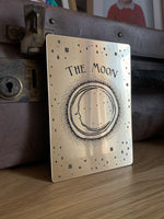 Load image into Gallery viewer, A decorative tarot card with etched design of a crescent moon, stars and the words &#39;the moon&#39;
